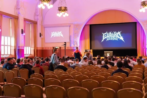 A view of the congress hall from the back. A metal-style Euruko Helsinki logo on the screen.